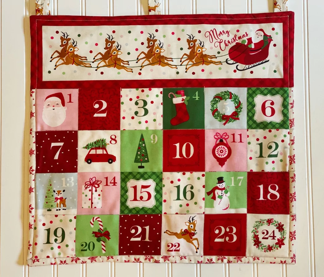 Hanging fabric advent calendar with numbered pockets filled with small gifts and candy canes.